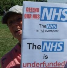 Jan Williams holding sign 'The NHS is not overspent. The NHSis underfunded.' 